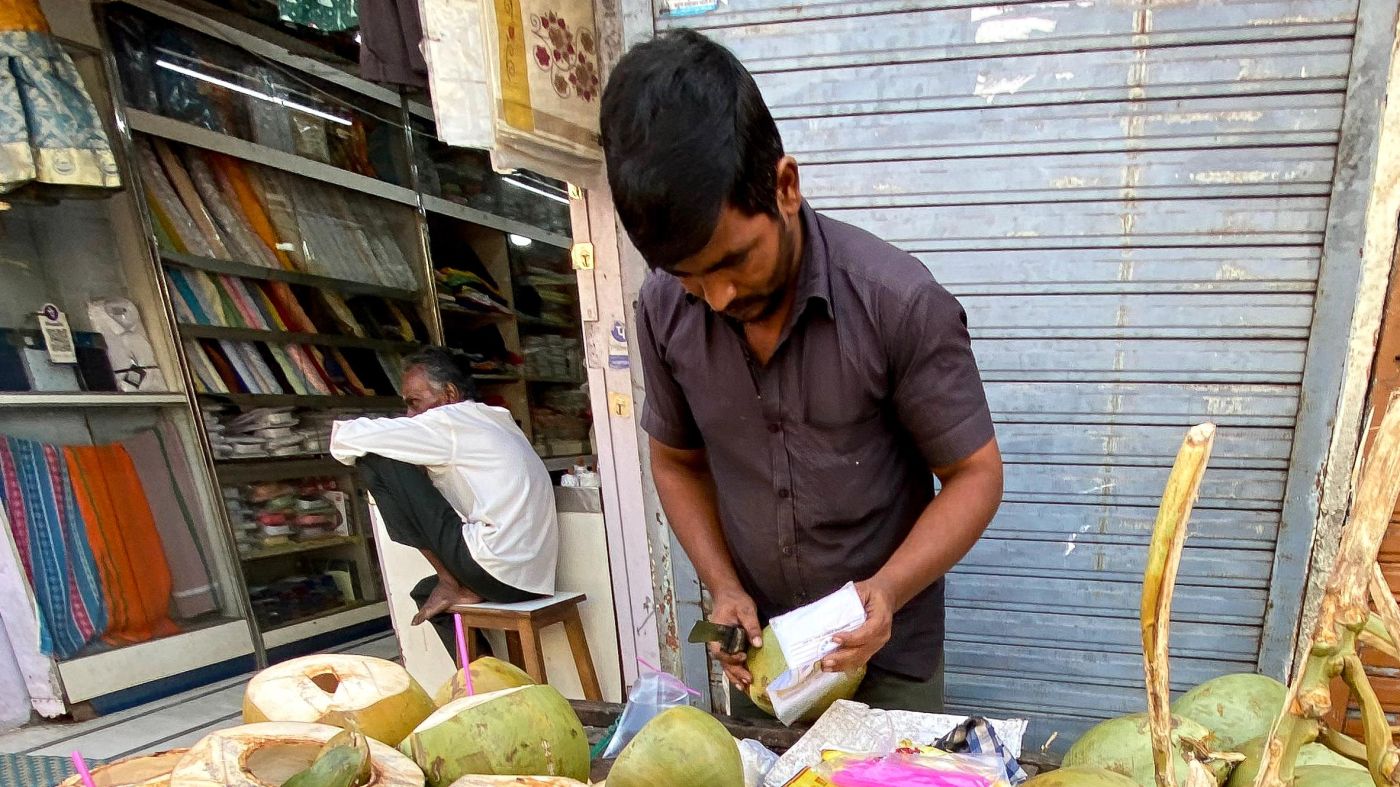 Kausar packing fresh coconut water in a small plastic bag for takeaway
