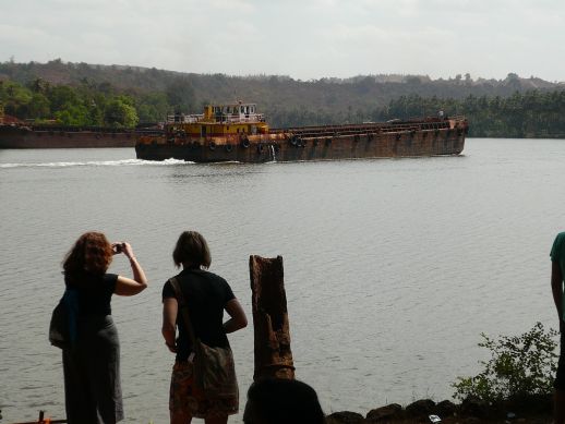Two students of the Royal Institute of Arts taking pictures of a barge transporting Iron ore on the Mandovi river
