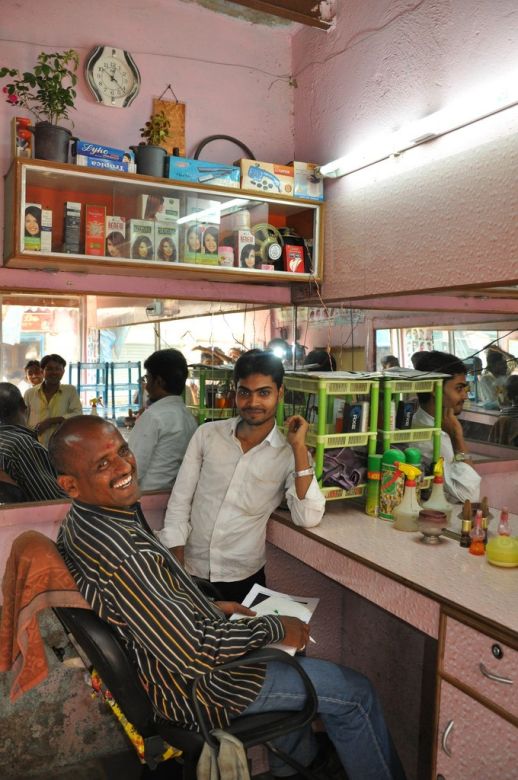 Salim Khan´s hair studio. Salim (in a white shirt) lives in the same space where he works. The prices are regulated by Dharavi´s barbers` union.