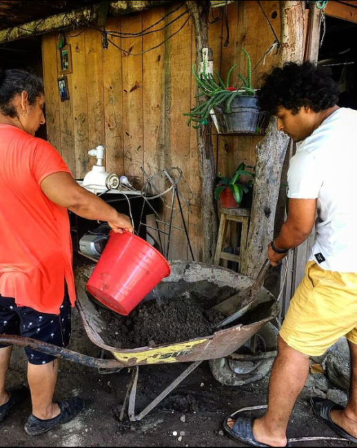 Tobias and Lucina mixing and pouring gravel and cement to temporarily repair damage caused by floods to the patio of Lucina’s home