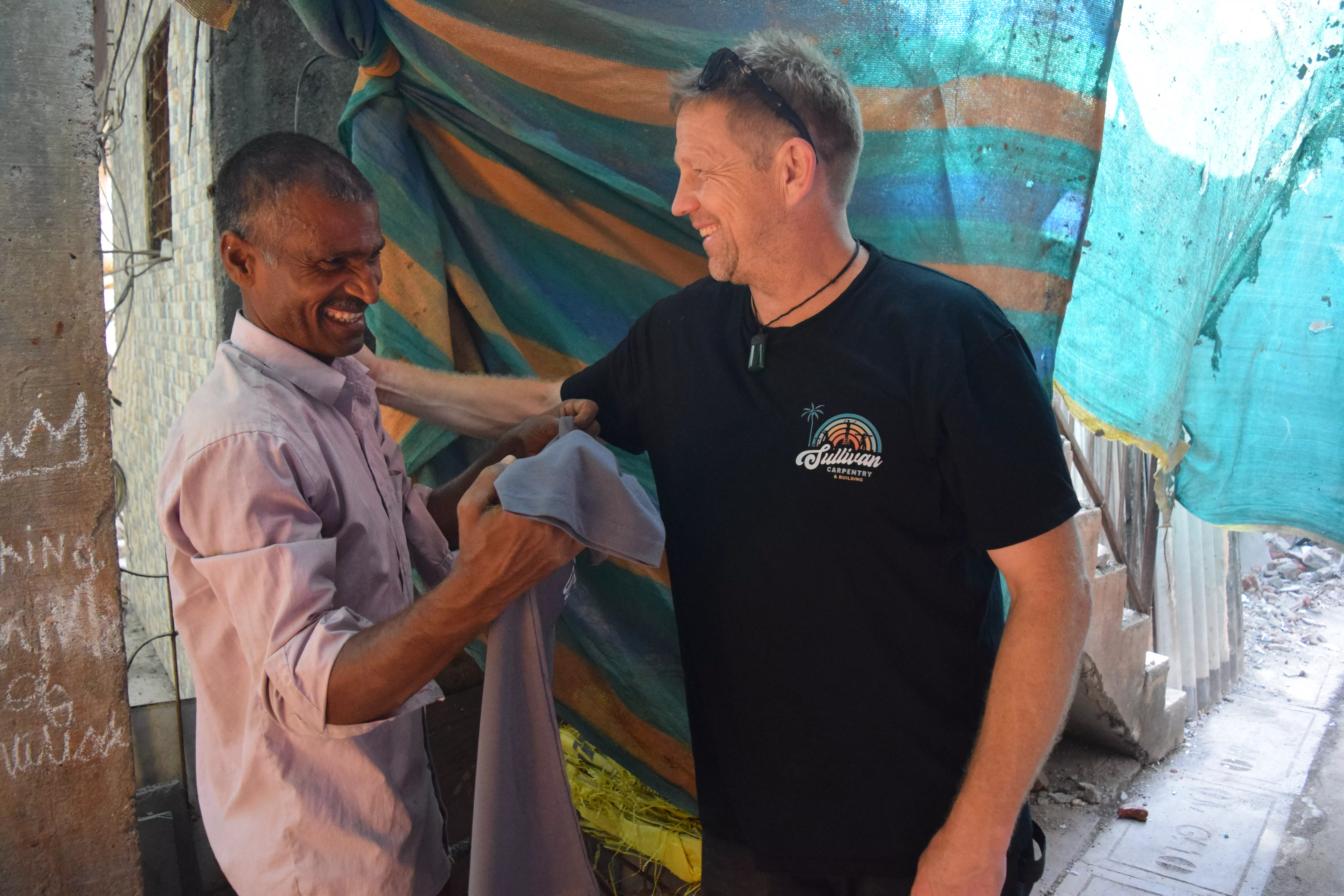 Richard gifts a Sullivan Carpentry T-shirt to Kishan