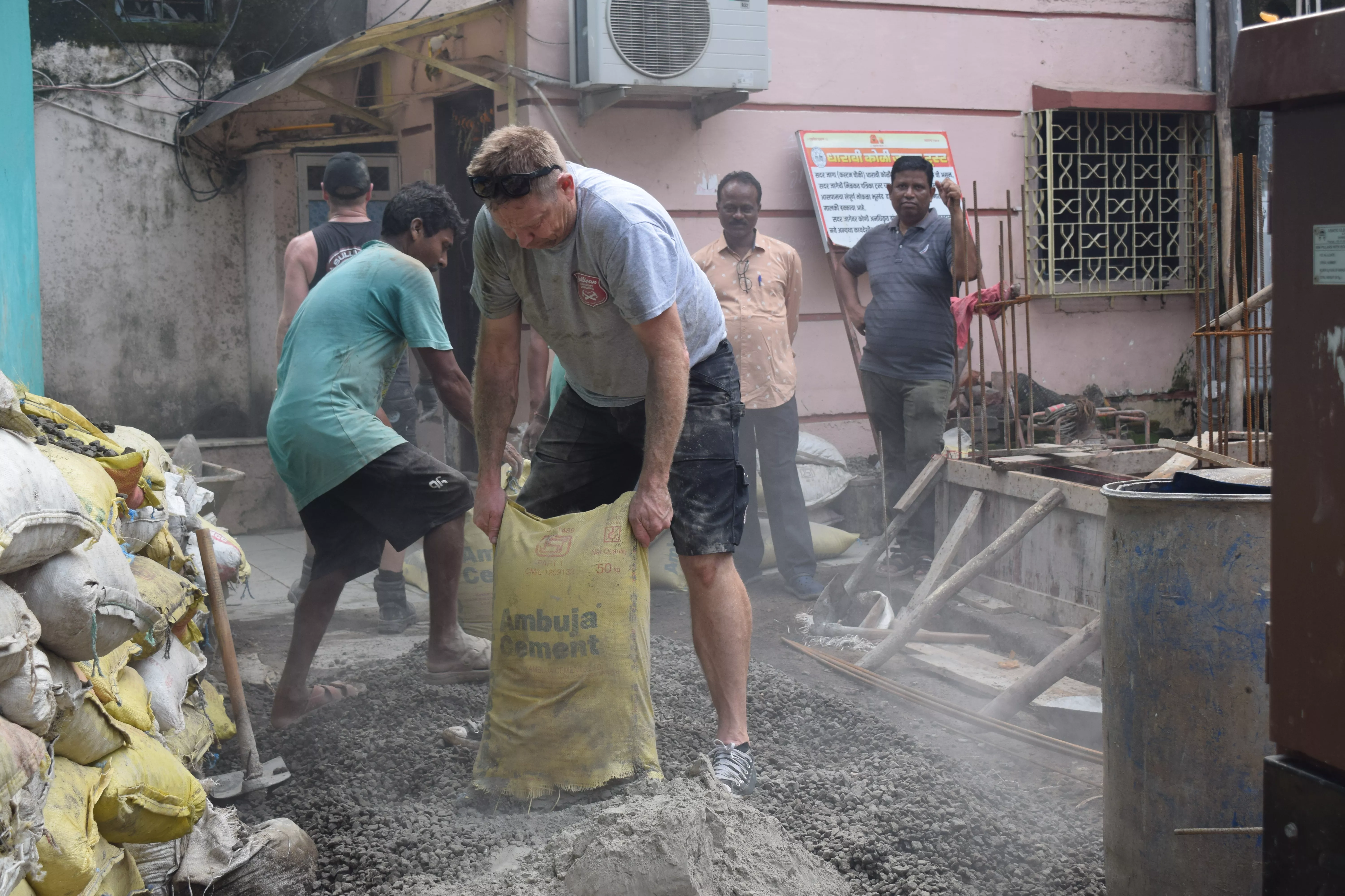 Richard Sullivan helping Manoj to mix cement and aggregate