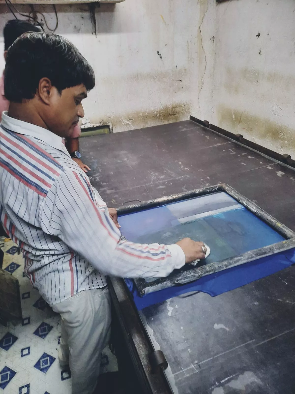 Samsuddin demonstrating the process of printing a t-shirt.