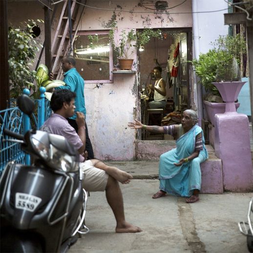A worker watches his neighbourhors chat on a porch. Back alleys are full of a variety of uses. Homes themselves often double up as work spaces. (Photo by Ishan Tankha for urbz).