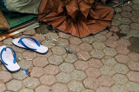 An umbrella fixer sits under his makeshift shelter (left). A metal hoop provides tension for the shelter (right)